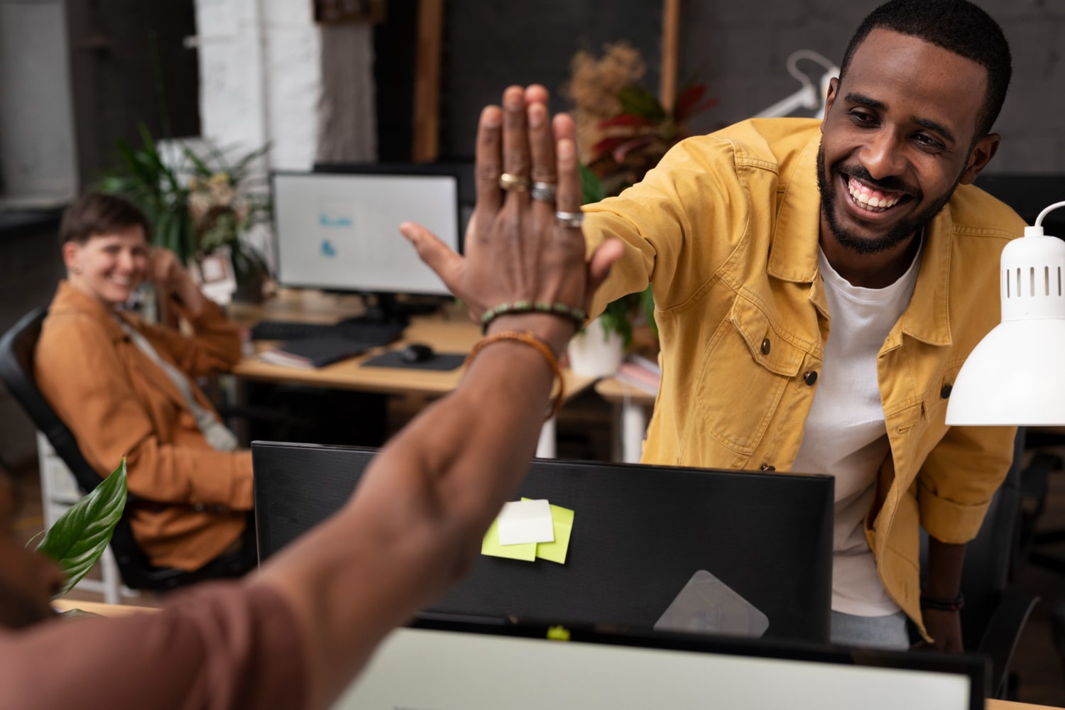 Dois homens fazendo o comprimento de "hi-five" em um escritório.